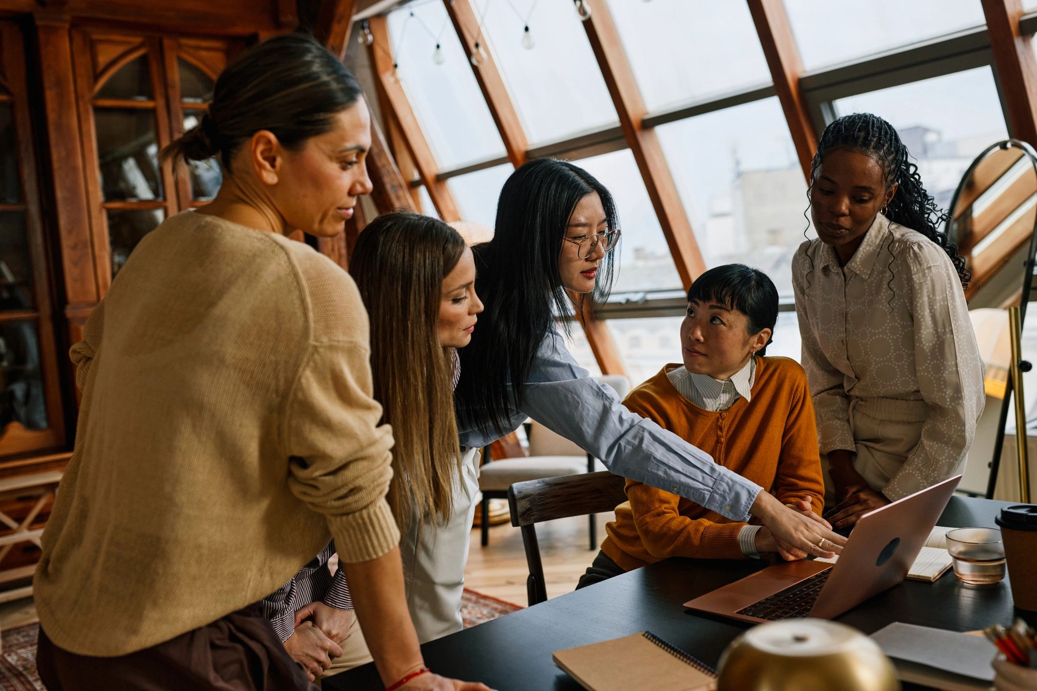 People collaborating around a laptop in a supportive group setting
